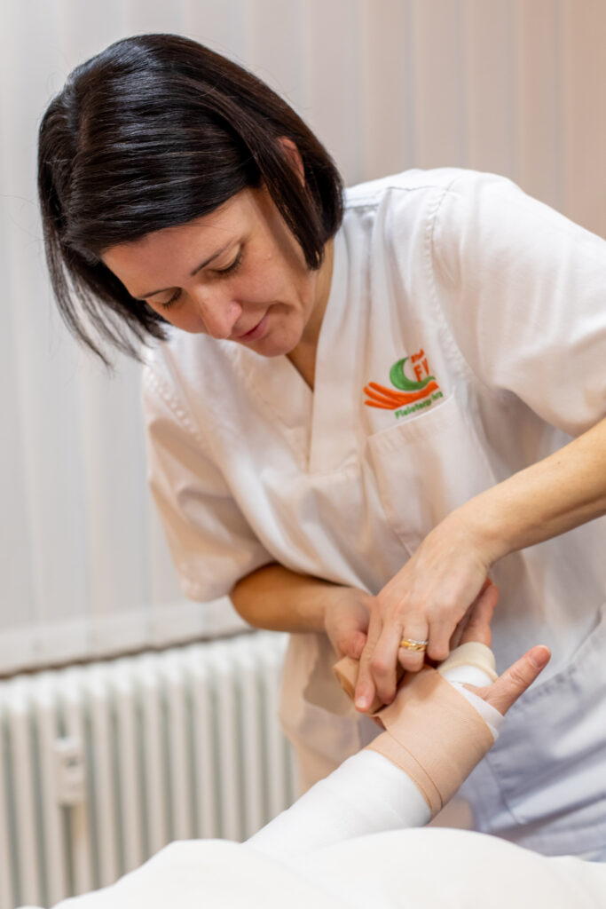 fisioterapista fa bendaggio a paziente per linfedema